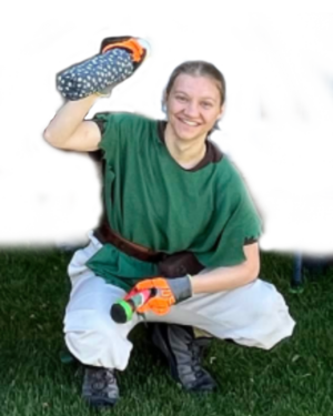 Valiant crouching, smiling, weapon raised, looking at the camera.